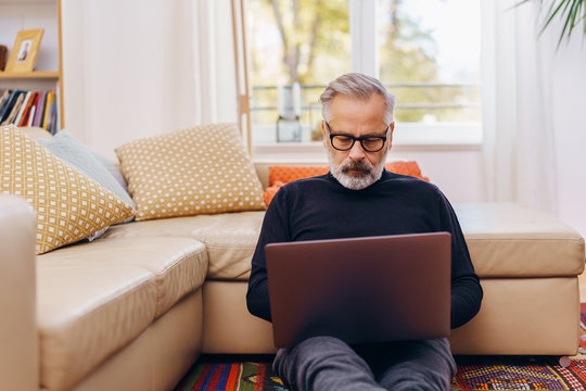 Senior man sitting using a laptop at home