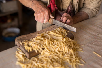 Elderly woman cutting pasta
