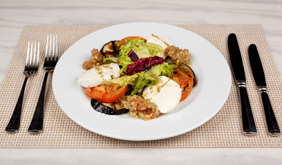 White cheese salad with tomato, eggplant and cabbage on a plate.