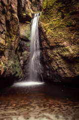 Fototapeta na wymiar A small waterfall fills the cave pond in Rock City, Adrspach, Czech Republic.
