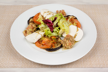 White cheese salad with tomato, eggplant and cabbage on a plate.