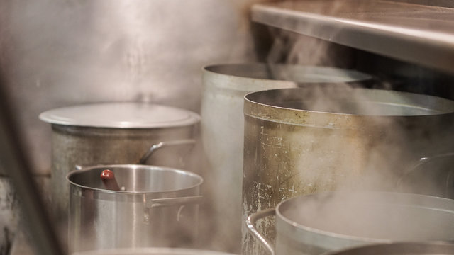 Assorted pots on a stove in an industrial kitchen
