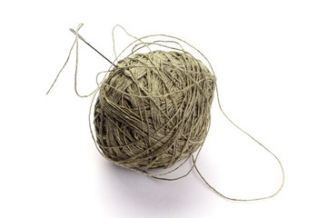 Coarse thread ball and needle on white background. Linen coarse gray threads and needle.