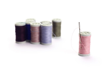  Different color spools of thread with needle.