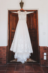 Fototapeta na wymiar Beautiful A-line wedding dress with floral embroidery is hanging in the morning of a wedding day