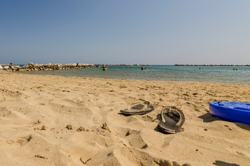 Fototapeta na wymiar Spiaggia con veduta mare e ciabatte infradito in primo piano