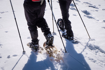 Close-up of two men hiking with snowshoes through snow on winterday