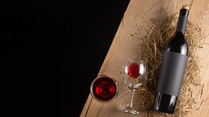 A bottle of red wine with a label on the old board. Glass of wine. A mock up bottle of wine. View...