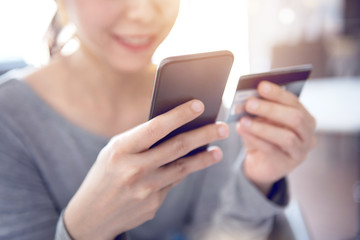 Happy woman shopping online with credit card using smartphone at home. Indoor