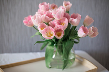 A bouquet of spring beautiful flowers in a glass vase. Fresh Pink tulips on white background.