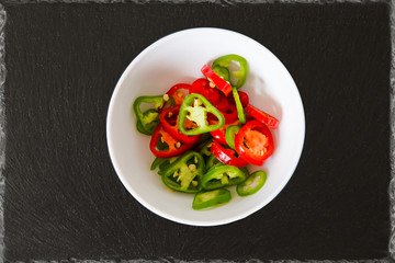 medium hot serenade chillies chopped red and green in a round bowl with black slate backgrade