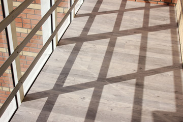 Lattice shadow on the terrace. Wooden floor, panoramic windows, abstract background.