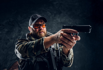 Special forces soldier holding a gun and aiming at the enemy. Studio photo against a dark textured...