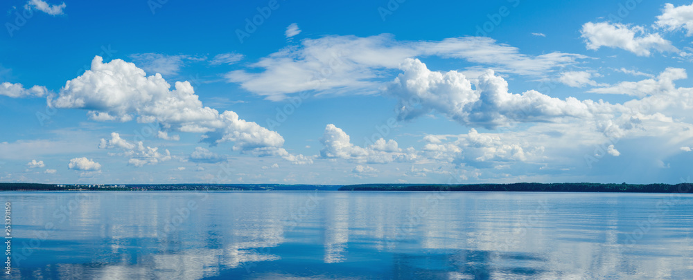 Wall mural panorama of calm lake, kama river blue sky with clouds reflected in the water.