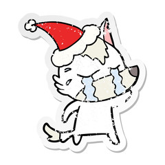 distressed sticker cartoon of a crying wolf wearing santa hat