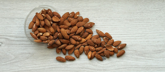 Healthy food  for background image close up almond nuts. Texture on white grey table top view. Nut on the cup plate