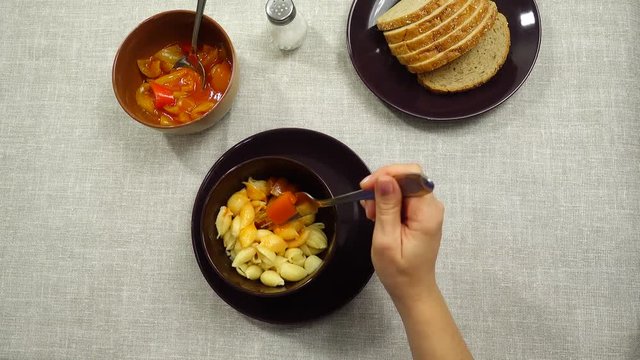 The process of eating pasta with lecho sauce.