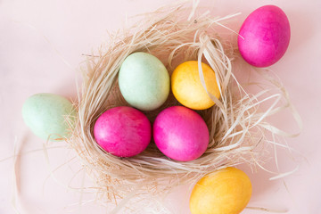 Fototapeta na wymiar pink , yellow, green Easter eggs in the nest, chicken boiled Easter eggs