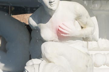 stone statue of a semi-nude woman holding her breast with her hand, breast cancer concept