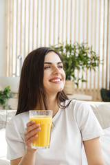 Brunette woman with closed eyes holding glass with orange juice