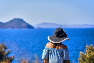 Beautiful woman in beach hat enjoying sea view with blue sky at sunny day in Bodrum, Turkey. Vacation Outdoors Seascape Summer Travel Concept