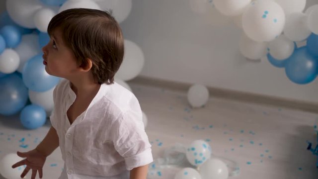 two year old boy playing with blue balloons