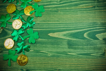 St Patricks Day corner border of shamrocks and gold coins on green wood background