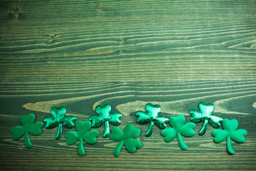 Glittery shamrocks on a wooden green background with space