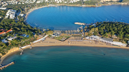 Obraz premium Aerial drone photo of iconic turquoise sandy celebrity beach of Asteras or Astir and ancient temple of Apollo Zoster, Vouliagmeni, Athens riviera, Attica, Greece