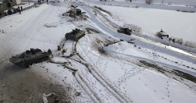 Tanks, armoured vehicles in snow-covered fields, soldiers fighting, shooting, explosions during an Afghanistan battle reconstruction near Minsk, Belarus