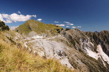 Fototapeta na wymiar Alpi Apuane above the white marble quarries of Carrara. A landscape with Mount Sagro with clear sky and clouds. (Carrara, Toscana, Italy)