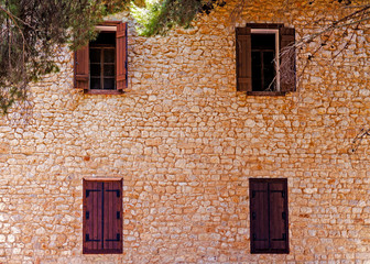 Fototapeta na wymiar An old wall with four windows in Greece