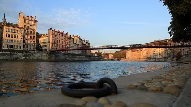 Pedestrians walking on an old footbridge over the Saone river during sunrise. Lyon, France.