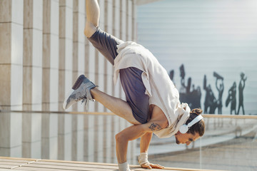 Attractive athletic man practicing yoga with maces outdoors in modern park.