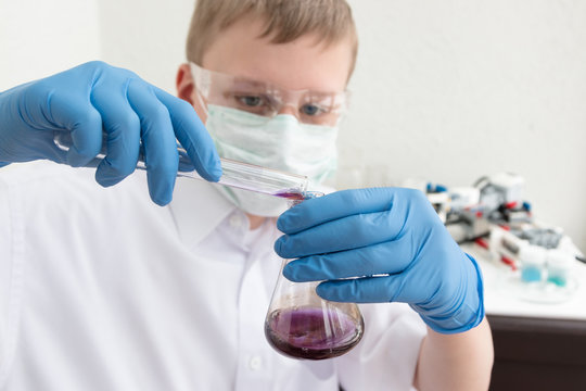 Science school, Medicine. A teenager boy conduct chemical experiments with tubes. On the table is a robot. STEM and STEAM education. Science and technology. Chemistry lab.
