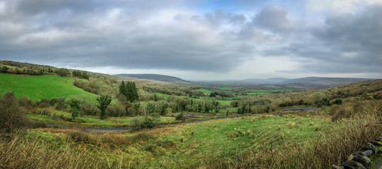 Panoramic View of Irish Countryside - with a Twisting Road in the Middle, and Cloudy Skies in the Background