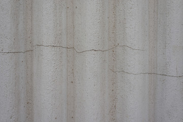 Graue Wand mit rauen Wellen und Rissen in der Wand