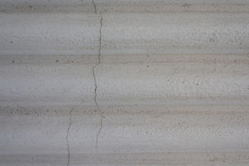 Graue Wand mit rauen Wellen und Rissen in der Wand