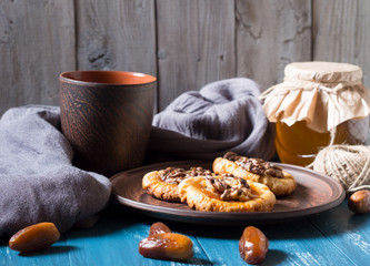 Romantic morning still life, in a rustic style with cookies, a glass jar of honey and scattered dates on a turquoise wooden background