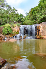 Fototapeta premium Waterfall and lake in rain forest of Moeda in Minas Gerais state on cloudy day among rocks and vegetation