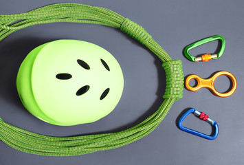 Climbing and mountaineering gear equipment such as rope, carabiner and helmet flat lay top view on gray background