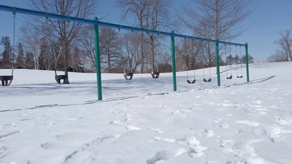 empty  playground, swing. Cute little boy (toddler, two year old) in hat with fur trim and earflaps. Child, winter time, cold weather, outdoor