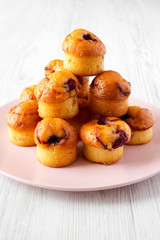 Homemade muffins with cherry on pink plate on a white wooden background, side view. Close-up.