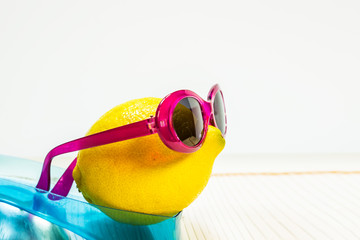 Lemon with glasses in profile on a blue stand on a white background, closeup photo