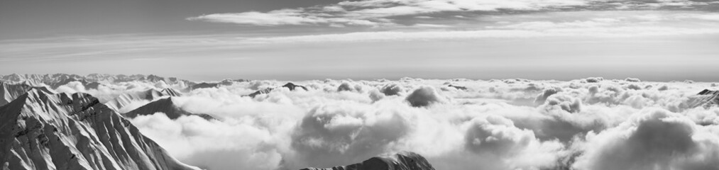 Obraz premium Panorama of snowy mountains covered with sunlight clouds at winter