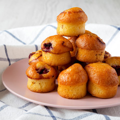 Homemade mini muffins with cherry on pink plate, side view. Closeup.