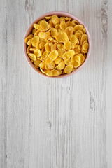 Top view, corn flakes in a pink bowl for breakfast on a white wooden background. Flat lay, from above. Copy space.