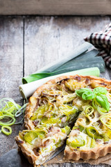 Leek tart with bacon and cheese on wooden table
