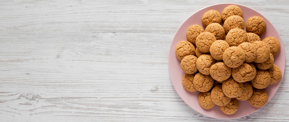 Almond cookies on pink plate on white wooden surface, overhead view. Flat lay, top view, from above. Space for text.
