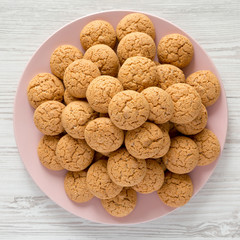 Top view, almond cookies on pink plate on a white wooden table. Flat lay, overhead, from above.
